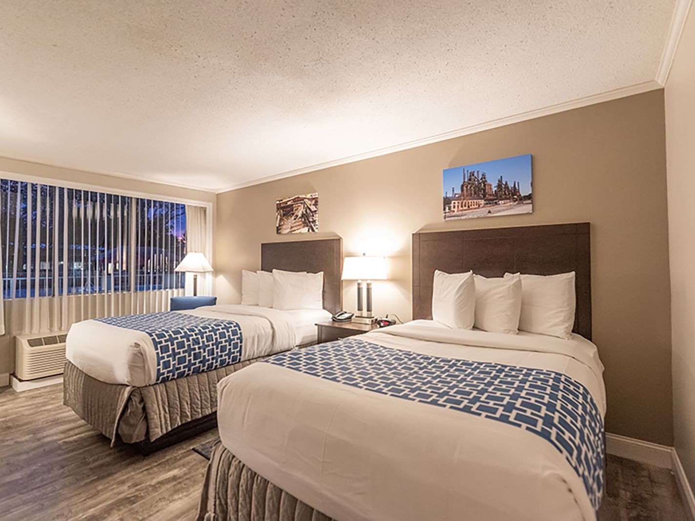 two beds in lit room with window